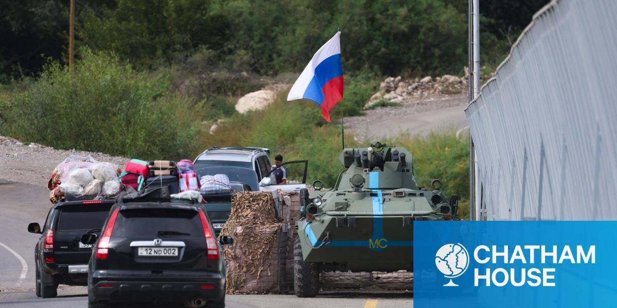 Cars passes next to a Russian peacekeeper vehicle, as they leave Karabakh to Armenia