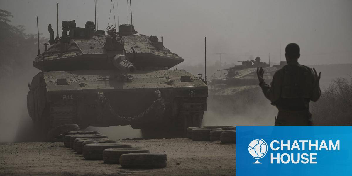 An Israeli soldier directs a Merkava battle tank as it deploys with other tanks along the border with the Gaza Strip in southern Israel on October 13, 2023.